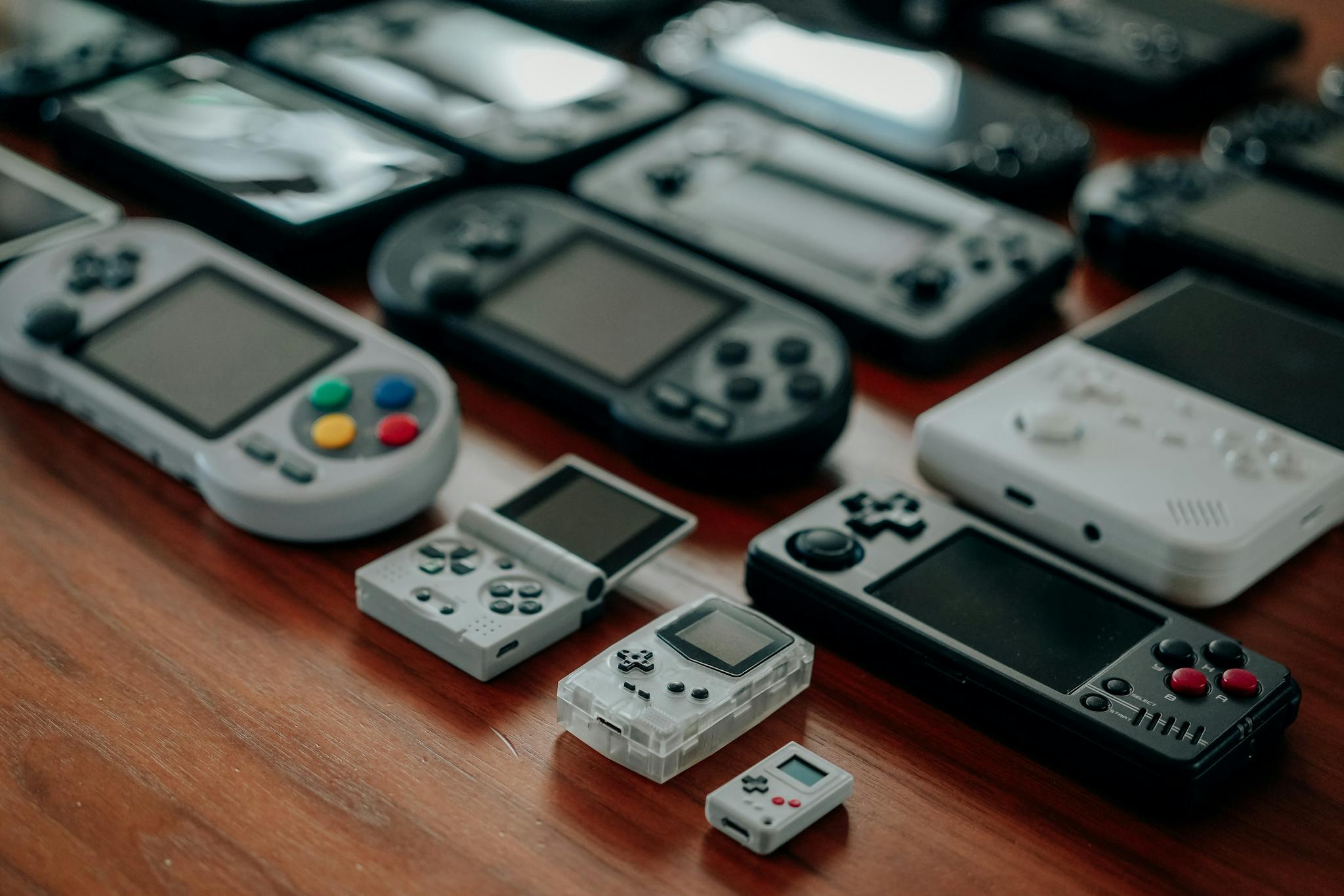Collection of diverse retro handheld gaming consoles on a wooden surface, showcasing classic designs and nostalgia. Deeravir